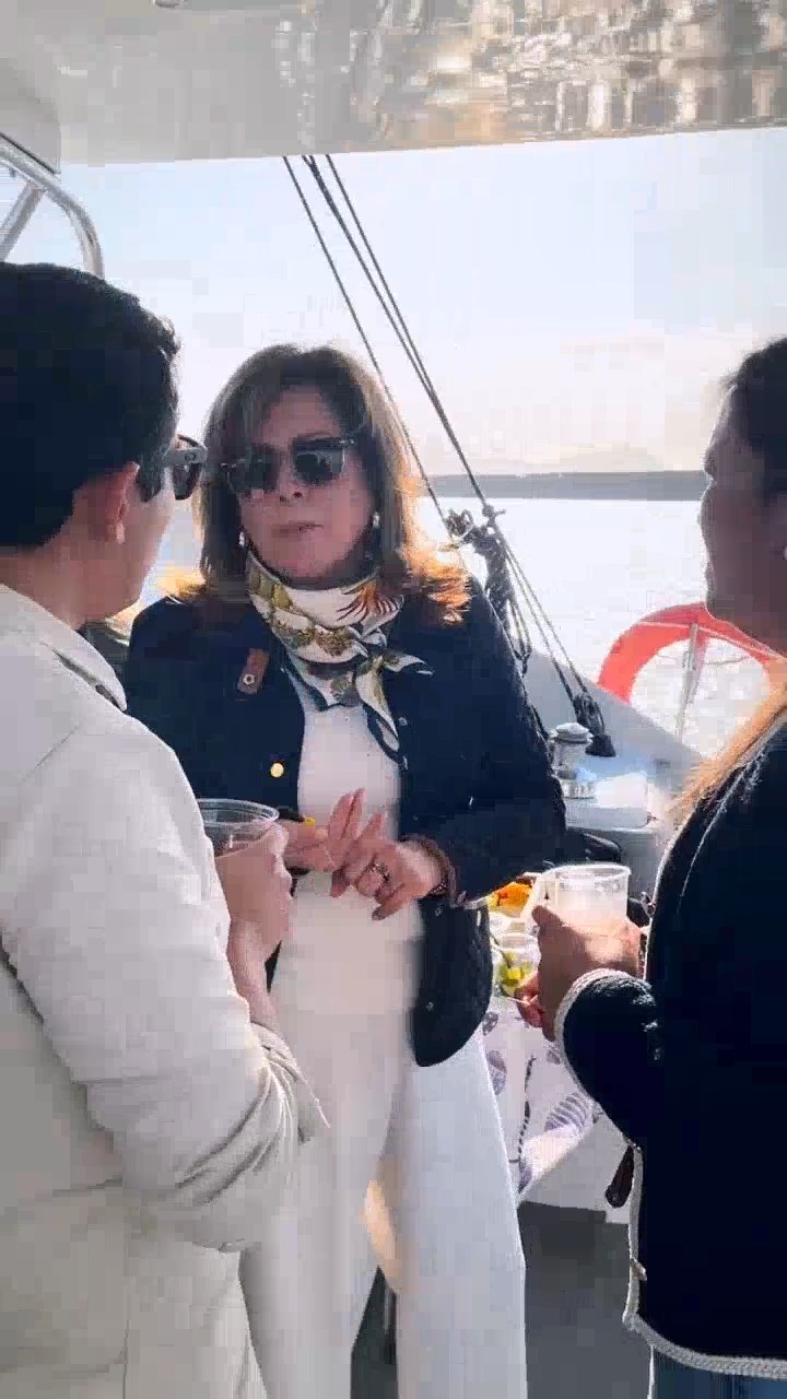 Tres asistentes conversando de pie en la cubierta con un trago en la mano