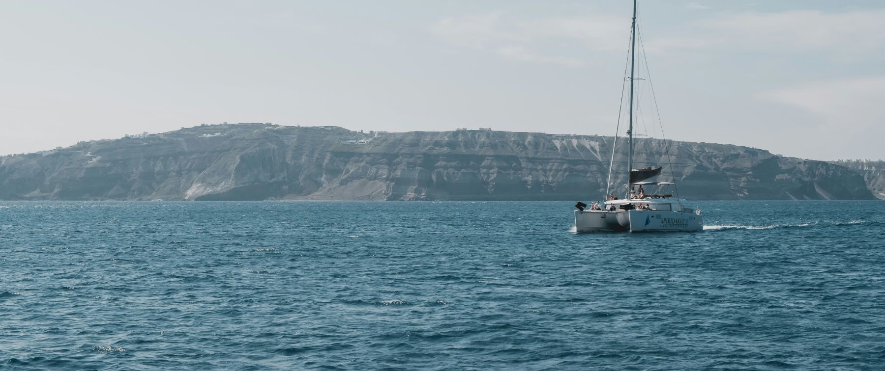 Catamarán navegando frente a los acantilados, con la cohorte a bordo
