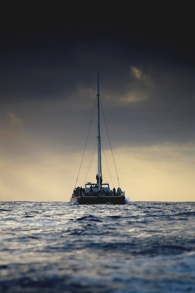 Catamarán navegando al atardecer con la cohorte en cubierta